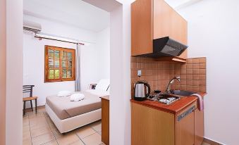 a small kitchenette with a sink , stove , and refrigerator next to a bed in a room at Matala Bay Hotel & Apartments