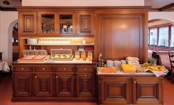 a wooden buffet table with a variety of food items , including fruits and pastries , is set up in a room at Hotel Astoria
