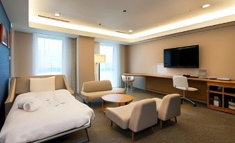 a modern hotel room with a large bed , seating area , and flat screen tv , all arranged in a minimalist style at Daiwa Roynet Hotel Numazu