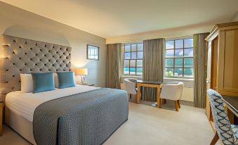 a hotel room with a comfortable bed , a desk , and a window overlooking the ocean at Slieve Russell Hotel