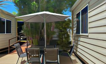 a patio with a table and chairs , an umbrella , and a house in the background at Mareeba Motor Inn