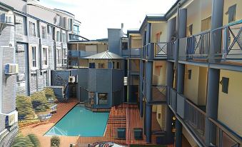 an outdoor courtyard with a swimming pool surrounded by multiple apartment buildings , creating a unique and inviting atmosphere at Airport Inn and Suites