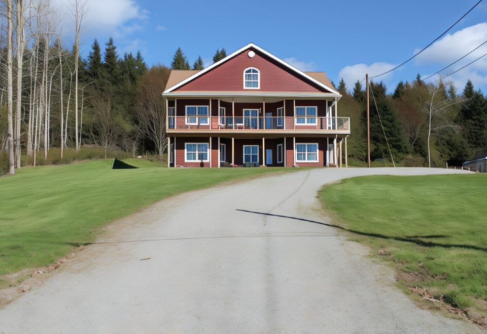 a large , two - story house with a red roof and white walls is surrounded by green grass and trees at The Fiddle and the Sea Bed and Breakfast