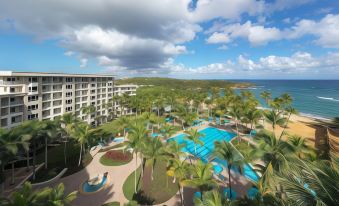 a luxurious hotel with a large pool surrounded by palm trees and a beach in the background at Hyatt Vacation Club at Hacienda del Mar