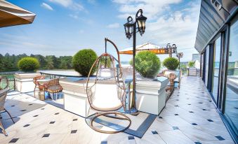 a rooftop terrace with a unique , large white wicker chair hanging from a metal pole at Garden Palace