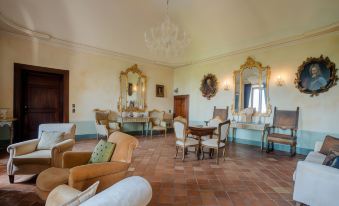 a spacious , well - decorated living room with large windows , wooden floors , and various furniture pieces including sofas , chairs , tables , and at Castello di Semivicoli