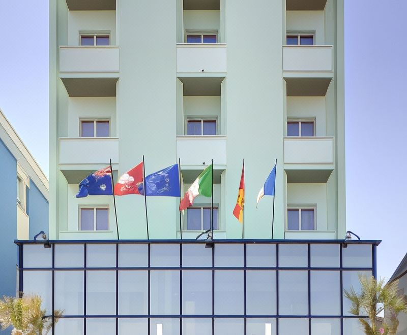 a tall building with a glass facade has several flags on top of the entrance at San Marco