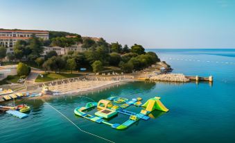 a large inflatable water park is located on the shore of a body of water at Maistra Select Riva Apartments