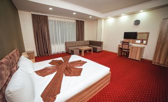 a hotel room with a large bed , couch , and tv , all neatly arranged in a red carpeted area at Continental Hotel