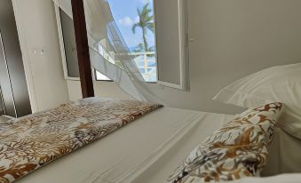 a bed with a white canopy and a patterned pillow is shown in front of a window at Majesty Palm