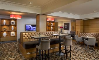 a modern bar area with a brown leather couch , a tv , and several chairs arranged around it at The Park Royal Hotel & Spa