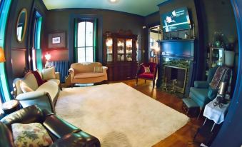 a cozy living room with hardwood floors , a fireplace , and various pieces of furniture such as a couch , chairs , and a television at Susquehanna Manor Inn