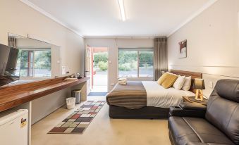 a spacious bedroom with a large bed , a bathroom , and a door leading to a patio at Black Forest Motel