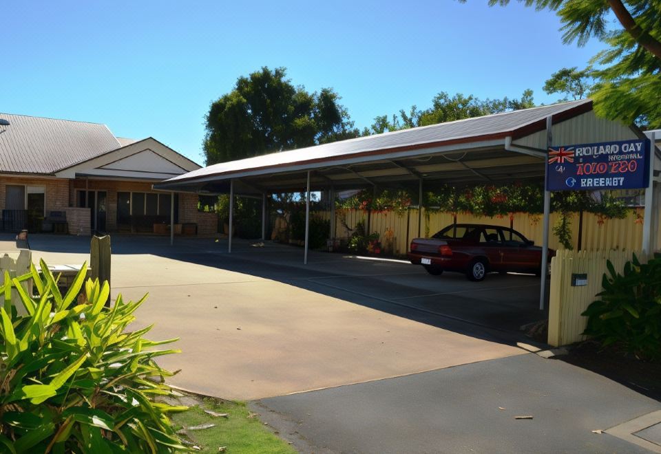 a car parked under a large white metal carport in front of a brick house at Redland Bay Motel