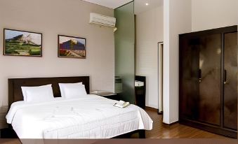 a large , well - made bed is the centerpiece of a hotel room with wooden flooring and white walls at Sevilla Resort Magelang
