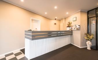 a modern office reception area with a white and gray counter , black and white checkered floor , and a large window at Mahoneys Motor Inn