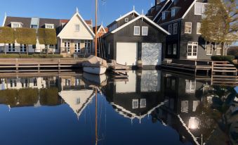 a boat docked on a body of water in front of several buildings , creating a picturesque scene at Fletcher Hotel - Restaurant Nautisch Kwartier