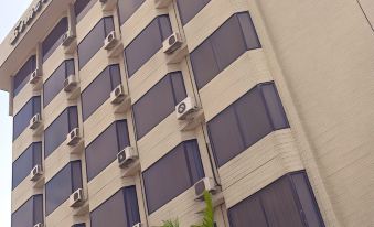 a tall building with blue and white stripes is shown next to a palm tree at Somerset Hotel