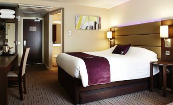 a hotel room with a large bed , white and purple bedding , and a painting on the wall at Taunton Ruishton (M5, J25)