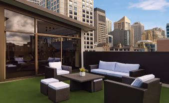 a rooftop patio with a green rug , couches , and chairs arranged around a coffee table at Vibe Hotel Sydney