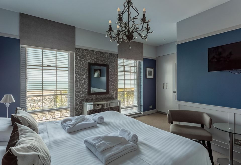 a bedroom with a large bed , chandelier , and windows overlooking the ocean , creating a serene atmosphere at Victoria Hotel