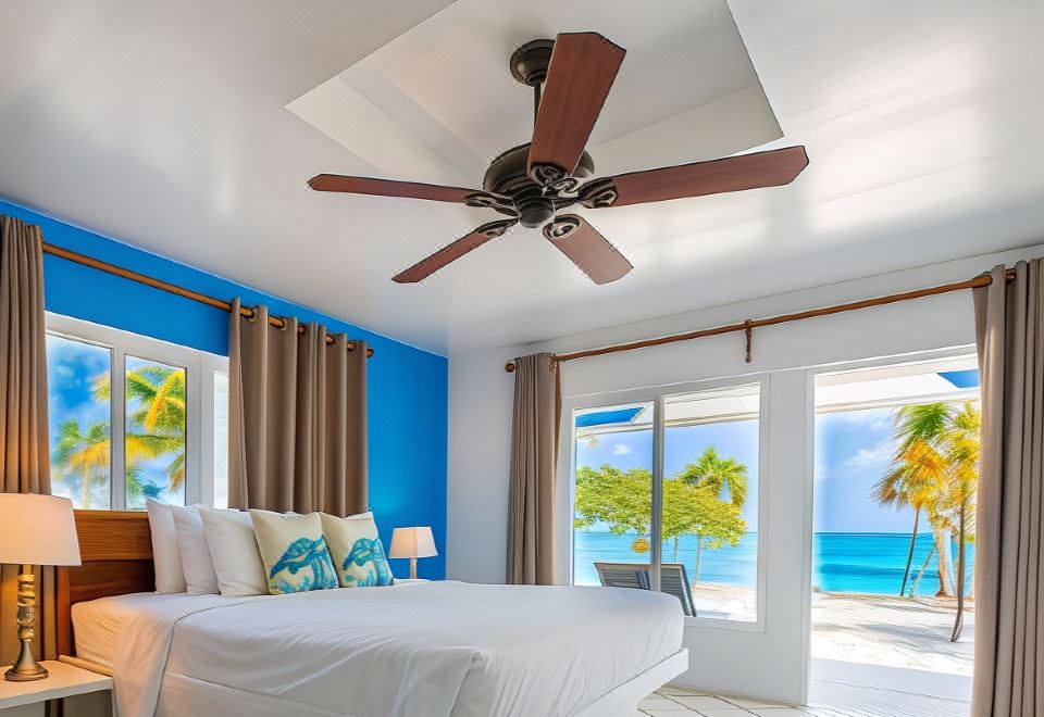 a bedroom with a large bed , a ceiling fan , and a view of the ocean at Pelican Beach Hotel