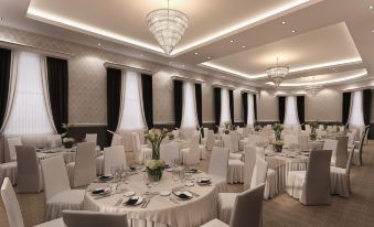 a large , elegant banquet hall with numerous round tables covered in white tablecloths and adorned with centerpieces at Villiers Hotel