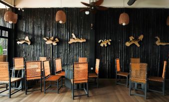 a modern restaurant with wooden chairs and tables , a black wall decorated with birds and other objects , and ceiling fans hanging from the ceiling at The Happy 8 Retreat @ Kuala Sepetang