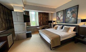 a luxurious bedroom with a king - sized bed , two paintings on the wall , and a flat - screen tv mounted on the wall at Queen's Hotel - Zebra Centre