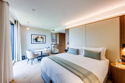 a modern hotel room with a large bed , white walls , and a minimalist design style at Oval Hotel at Adelaide Oval, an EVT hotel