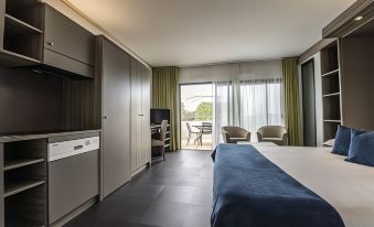 a bedroom with a bed , chairs , and a television near a sliding glass door leading to a balcony at Suite Home Porticcio