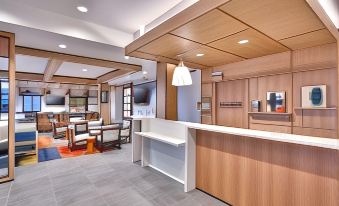 a modern hotel lobby with a white reception desk and seating area , surrounded by wooden ceiling beams at Hyatt House Provo/Pleasant Grove