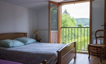 a bedroom with a large bed and wooden furniture , overlooking a balcony with a view of trees at Chez Pierre