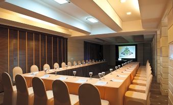 a long dining table set up for a meeting , with multiple chairs arranged around it at Crown Victoria Hotel Tulungagung