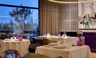 a restaurant with multiple tables set up for dining , each table having white tablecloths and purple place settings at Renaissance Aix-en-Provence Hotel