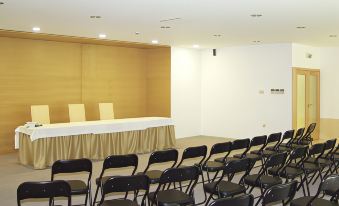 a conference room with rows of black chairs and a long table with a white tablecloth at Stay Hotel Guimarães Centro