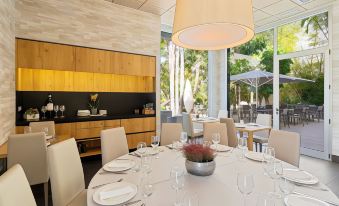 a dining room with a round table surrounded by chairs , and a kitchen in the background at Hotel Areca