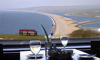 a table with two glasses of wine and a sculpture is set up in front of a window overlooking a body of water at Heights Hotel