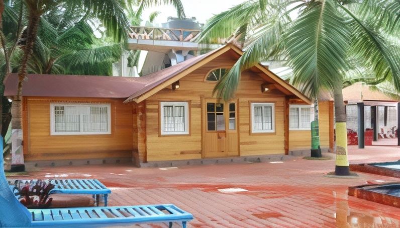 a wooden house with white windows and a brown roof , surrounded by palm trees and a blue bench at Bluebay Beach Resort