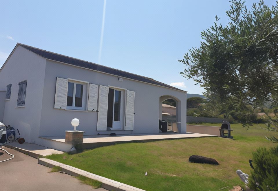 a white house with blue shutters and a large window is surrounded by green grass at Stella Marina