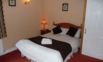 a bed with a brown blanket and white sheets is in a room with a red floor at Malt House