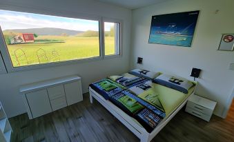 a bed with a colorful quilt is placed in front of a window overlooking a field at Beachin - Sport, Events, Hotel, Restaurant, Bar