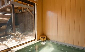 a japanese - style bathroom with a green bathtub and a large window overlooking the outdoors at Shikimitei Fujiya