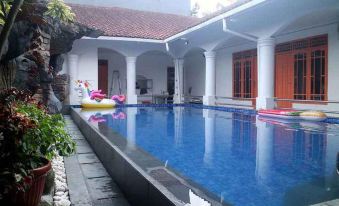 a large swimming pool is surrounded by a white building and a balcony with red columns at Mason Residence Syariah Ciawi