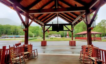 a wooden gazebo with multiple rocking chairs placed on the deck , creating a cozy atmosphere at Smoky Falls Lodge