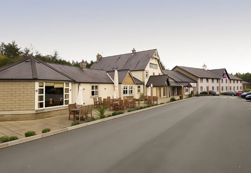 a street view of a row of houses with chairs and tables in front of them at Premier Inn Bangor (Gwynedd, North Wales)