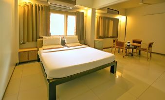 a large bed with white sheets and a green headboard is in the middle of a room at Hotel Sangam