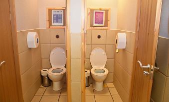 a public restroom with two toilets , one on the left and one on the right , along with two dispensers for trash cans at The Red Lion