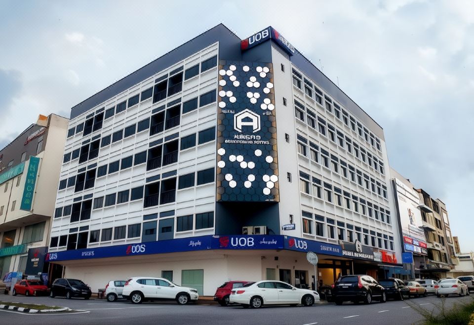 a modern building with a large white screen displaying the logo for uob , surrounded by cars on the street at Arena Boutique Hotel Kuala Terengganu