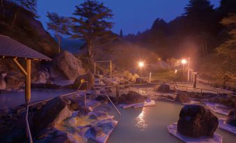 a group of people gathered around a hot tub in a natural setting , enjoying their time together at Manza Kogen Hotel